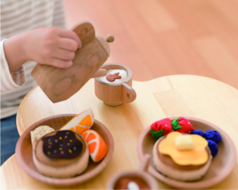 木のままごとセットのポットでお茶を淹れる画像
